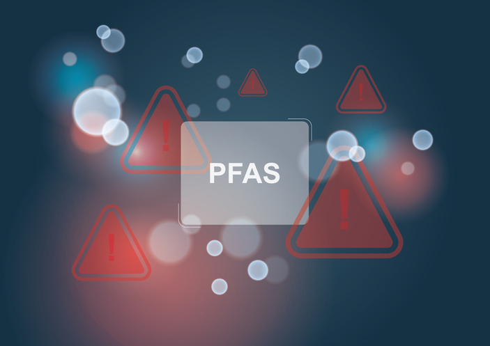 Abstract digital background with red warning triangles and light bokeh overlay surrounding the word ‘PFAS’ in the center, symbolizing environmental contamination or chemical hazard awareness.